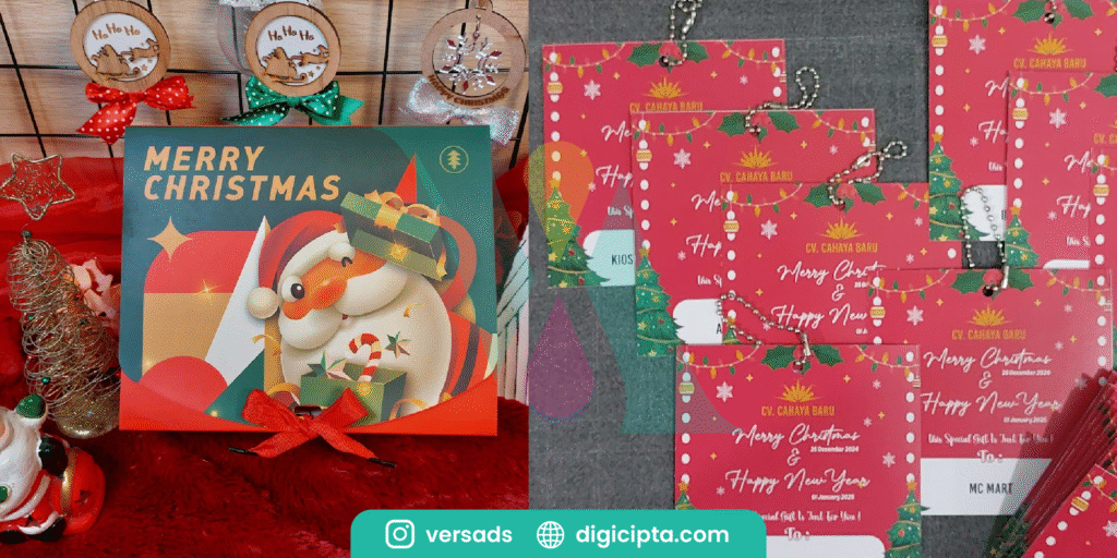 Kotak hadiah bertema Natal dengan ilustrasi Santa Claus dan tulisan “Merry Christmas”, dikelilingi ornamen Natal serta tag gantungan kartu ucapan merah bertuliskan “Merry Christmas & Happy New Year”.